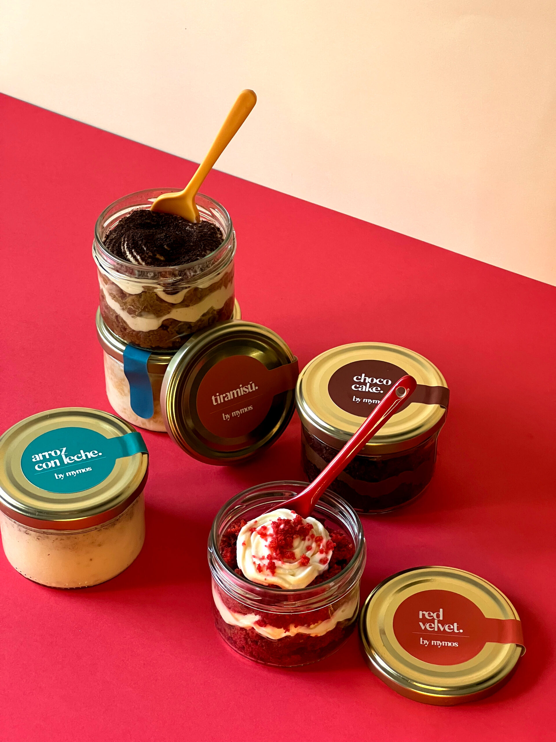 tarritos con postres dentro de marca mymos todos juntos sobre un fondo beige y rojo